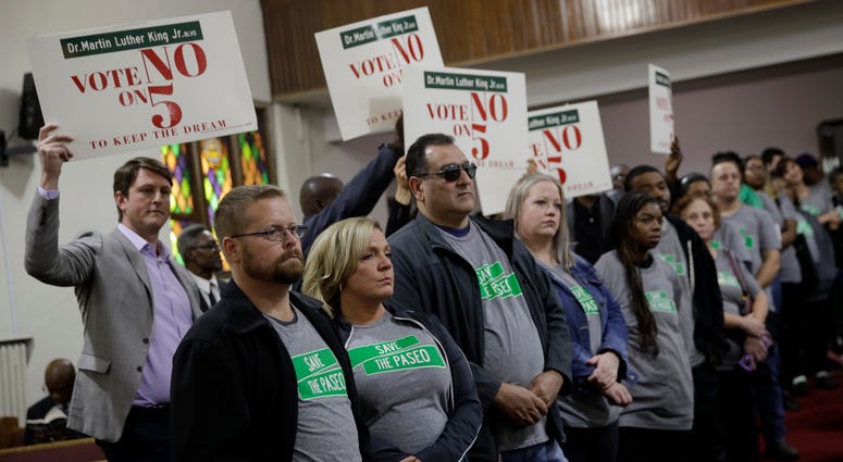 In this Sunday, Nov. 3, 2019, photo, people wearing "Save The Paseo" shirts stand among attendees at a rally to keep a street named in honor of Dr. Martin Luther King Jr. at Paseo Baptist Church in Kansas City, Mo. Save The Paseo protesters