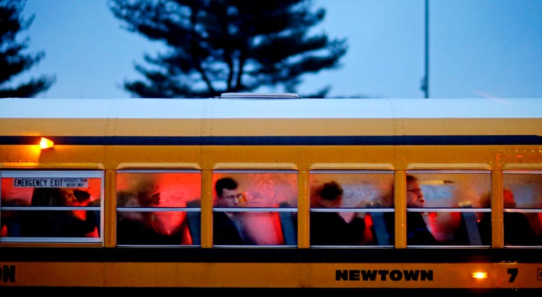 In this Dec. 16, 2012 file photo, people arrive on a school bus at Newtown High School for a memorial vigil attended by President Barack Obama for the victims of the Sandy Hook Elementary School shooting, in Newtown, Conn. Newtown High School