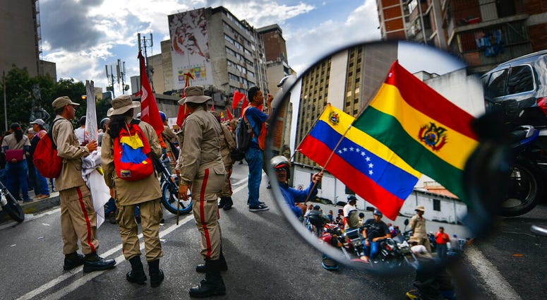 Reflected in a motorcycle side mirror, supporters of Venezuelan President Nicolas Maduro rally in support of former Bolivian President Evo Morales in Caracas, Venezuela, Monday, Nov. 11, 2019. Reflected in a motorcycle side mirror, supporters of Venezuelan President Nicolas Maduro rally in support of former Bolivian President Evo Morales in Caracas, Venezuela, Monday, Nov. 11, 2019.