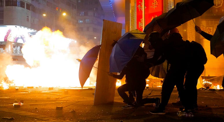 Protesters cover with umbrellas from tear gas canister in the Kowloon area of Hong Kong, Monday, Nov. 18, 2019. Protesters cover with umbrellas from tear gas canister in the Kowloon area of Hong Kong, Monday, Nov. 18, 2019.