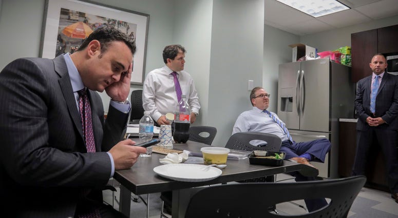 Attorney Adam Slater, left, checks his phone during a working lunch with lawyers in his firm. He said since New York opened its one-year window allowing sex abuse suits with no statute of limitations, his firm has signed up nearly 300 new clients. Attorney Adam Slater, left, checks his phone during a working lunch with lawyers in his firm.