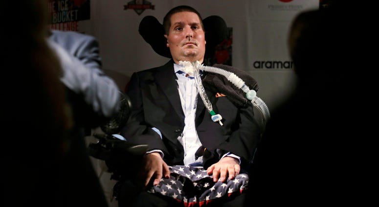 In this Sept. 18, 2017 photo, Pete Frates, who is stricken with amyotrophic lateral sclerosis, or ALS, listens to a guest at Fenway Park in Boston. Pete Frates