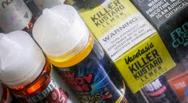 This Sept. 16, 2019 file photo shows flavored vaping solutions in a window display at a vape and smoke shop in New York. Flavored vaping solutions
