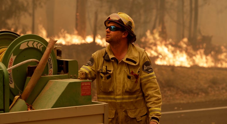 Australia's Prime Minister Scott Morrison called up about 3,000 reservists as the threat of wildfires escalated Saturday in at least three states with two more deaths. A Forest Corporation worker manages a fire hose as he battles a fire near Moruya, Australia, Saturday.