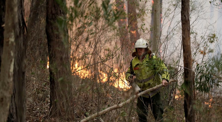 Milder temperatures Sunday brought hope of a respite from wildfires that have ravaged three Australian states, destroying almost 2,000 homes. A firefighter keeps an eye on a controlled burn used to control a larger fire near Burrill Lake, Australia, Sunday.