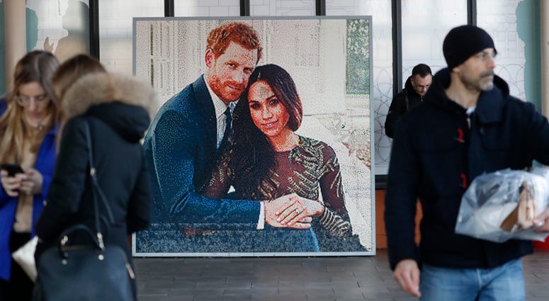 Britain's Prince Harry and his wife, Meghan, said they are planning "to step back" as senior members of the royal family and "work to become financially independent." People walk past a picture of Britain's Prince Harry and Meghan Duchess of Sussex, in Windsor, Friday.
