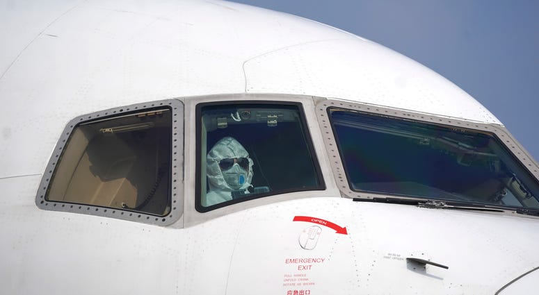 a pilot wearing a protective suit parks a cargo plane at Wuhan Tianhe International Airport in Wuhan in central China's Hubei Province, Tuesday, Jan. 28, 2020. A pilot wearing a protective suit parks a cargo plane at Wuhan Tianhe International Airport in Wuhan in central China's Hubei Province, Tuesday, Jan. 28, 2020.