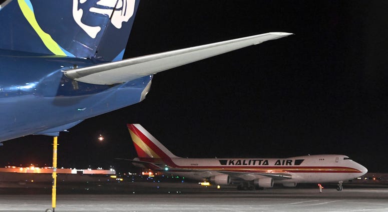 An airplane, background, carrying U.S. citizens being evacuated from Wuhan, China, makes a refueling stop at the north terminal at Ted Stevens Anchorage International Airport in Anchorage, Alaska Tuesday evening, Jan. 28, 2020. An airplane, background, carrying U.S. citizens being evacuated from Wuhan, China, makes a refueling stop at the north terminal at Ted Stevens Anchorage International Airport in Anchorage, Alaska Tuesday evening, Jan. 28, 2020.