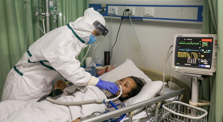 The number of confirmed cases of the new virus has risen again in China Saturday, Feb. 8, 2020. In this Thursday, Feb. 6, 2020, photo, a nurse feeds water to a patient in the isolation ward for 2019-nCoV patients at a hospital in Wuhan in central China's Hubei province.