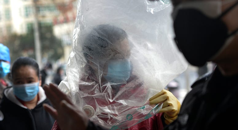 A man wearing a protective face mask covered himself with a plastic cover before enters a supermarket in Wuhan in central China's Hubei province, Monday, Feb. 10, 2020. A man wearing a protective face mask covered himself with a plastic cover before enters a supermarket in Wuhan in central China's Hubei province, Monday, Feb. 10, 2020.