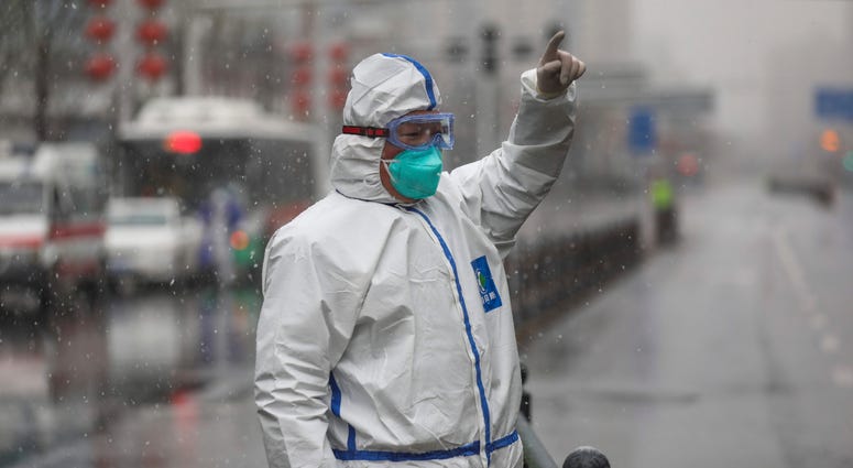 The Wuhan coronavirus is thought to have infected more than 67,000 people globally and has killed at least 1,526 people, the vast majority in China. A worker wearing a protective suit gestures to a driver outside a tumor hospital newly designated to treat COVID-19 patients in Wuhan in central China's Hubei Province, Saturday, Feb. 15, 2020.