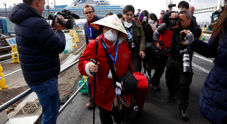 An unidentified passenger is surrounded by the media after she disembarked from the quarantined Diamond Princess cruise ship Wednesday, Feb. 19, 2020, in Yokohama, near Tokyo. An unidentified passenger is surrounded by the media after she disembarked from the quarantined Diamond Princess cruise ship Wednesday, Feb. 19, 2020, in Yokohama, near Tokyo.