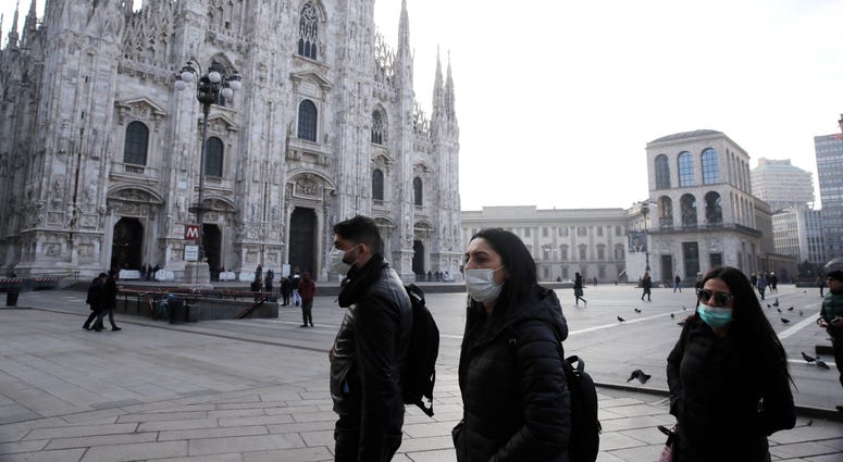 A rapid spike in new virus infections prompted authorities in the northern Lombardy and Veneto regions of Italy to close schools, businesses and restaurants and to cancel sporting events and Masses. People wearing sanitary masks walk past the Duomo gothic cathedral in Milan, Italy, Sunday, Feb. 23, 2020.