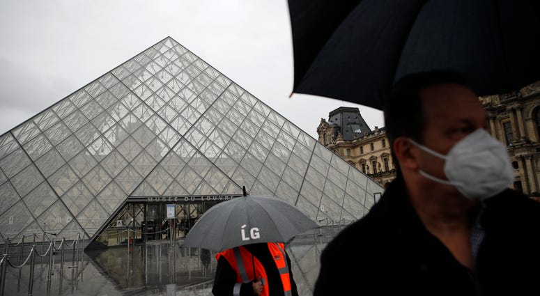 A tourist wearing a mask walks away from the Louvre museum in Paris, Monday, March 2, 2020. The Louvre Museum was closed again Monday as management was meeting with staff worried about the spread of the new virus in the world's most-visited museum. The Louvre was closed again for fear of coronavirus outbreak.