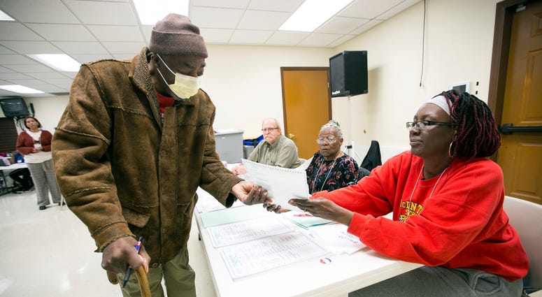 Henry Williams receives his ballot from first time election judge Kimberly Sims at United Faith Baptist Church in Rockford, Ill., Tuesday, March 17, 2020. Henry Williams receives his ballot from first time election judge Kimberly Sims at United Faith Baptist Church in Rockford, Ill., Tuesday, March 17, 2020.