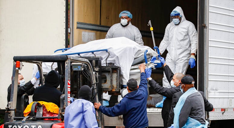 A body wrapped in plastic is unloaded from a refrigerated truck and handled by medical workers wearing personal protective equipment due to COVID-19 concerns, Tuesday, March 31, 2020, at Brooklyn Hospital Center in the Brooklyn borough of New York. A body rapped in plastic is unloaded from a refrigerated truck and handled by medical workers wearing personal protective equipment due to COVID-19 concerns, Tuesday, March 31, 2020, at Brooklyn Hospital Center in the Brooklyn borough of New York.