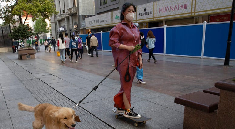 A resident gets a ride from her dog along a retail street in Wuhan in central China's Hubei province, Thursday, April 9, 2020. A resident gets a ride from her dog along a retail street in Wuhan in central China's Hubei province, Thursday, April 9, 2020.