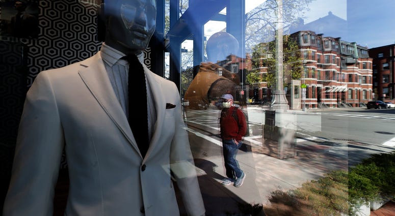 A passer-by wearing a mask out of concern for the COVID-19 coronavirus, background center, walks past mannequins in a clothing store, Wednesday, April 29, 2020, in Boston. A passer-by wearing a mask out of concern for the COVID-19 coronavirus, background center, walks past mannequins in a clothing store, Wednesday, April 29, 2020, in Boston.