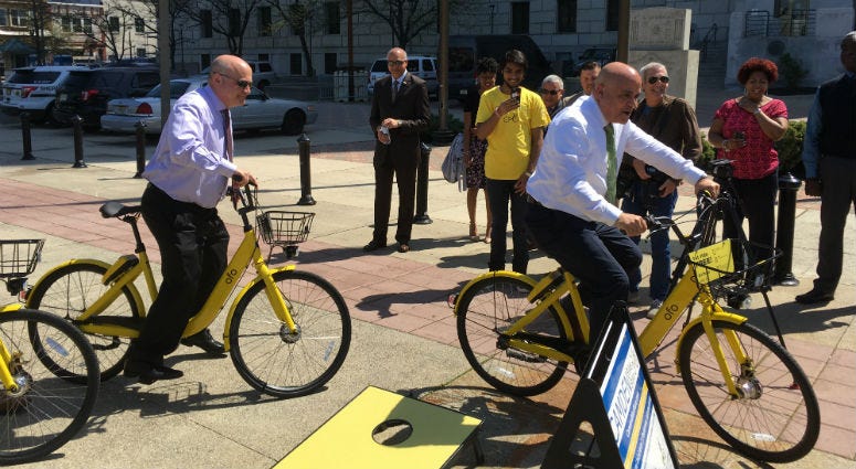 (From left) Camden County Freeholder Jeff Nash and Camden Mayor Frank Moran demonstrate Camden's new bike share equipment. Camden County Freeholder Jeff Nash and Camden Mayor Frank Moran