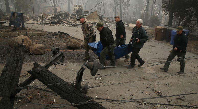 Yuba and Butte County sheriff deputies carry a body bag with a deceased victim of the Camp Fire on November 10, 2018 in Paradise, California. Crane company fires 3 employees after they post inappropriate pictures in Camp Fire wreckage