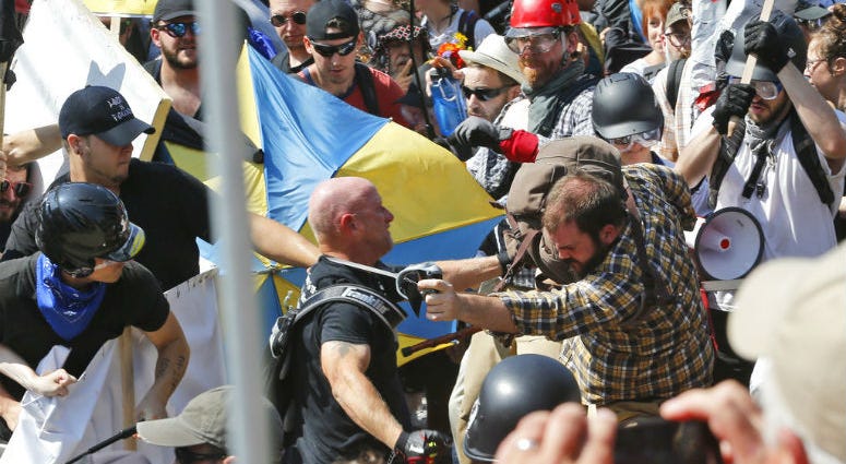 In this Aug. 12, 2017 file photo, white nationalist demonstrators clash with counter demonstrators at the entrance to Lee Park in Charlottesville, Va. The leader of a Southern California white supremacist group and three other members have been arrested.