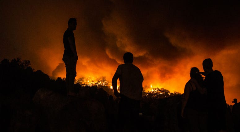 People stand next to the fire before being evacuated at the village of Monchique, in southern Portugal's Algarve region, Sunday, Aug. 5 2018. People stand next to the fire before being evacuated at the village of Monchique, in southern Portugal's Algarve region, Sunday, Aug. 5 2018.
