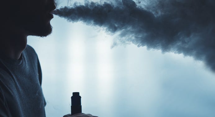 A man smoking an e-cigarette. A man smoking an e-cigarette.
