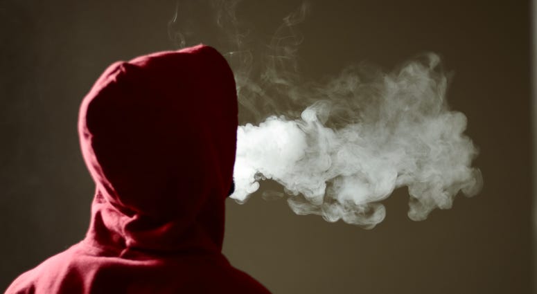 Young male in red hoodie vaping smoking, exhales thick vapor. Young male in red hoodie vaping smoking, exhales thick vapor.