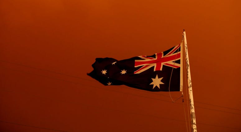 The Australia Flag flies under red skies from the fires on January 04, 2020 in Bruthen Australia. The Australia Flag flies under red skies from the fires on January 04, 2020 in Bruthen Australia.
