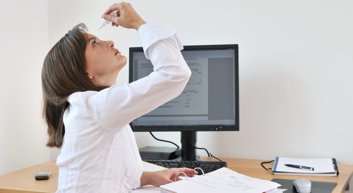 A person using eye drops. A person using eye drops.