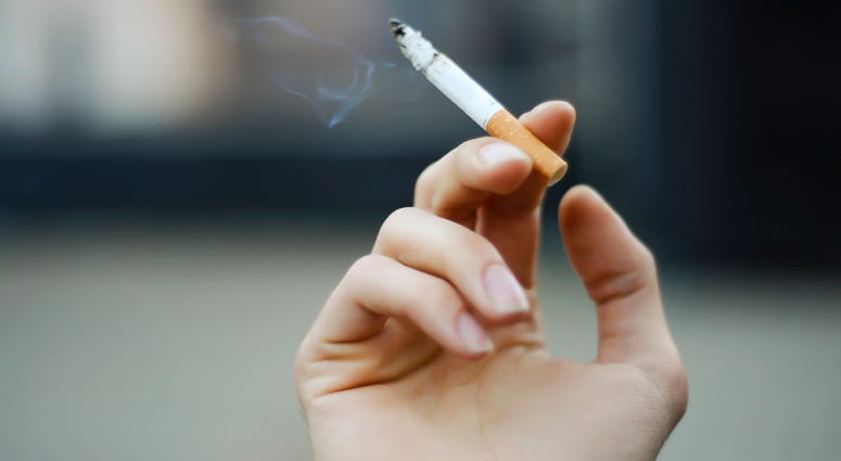 A person holding a cigarette. A person holding a cigarette.