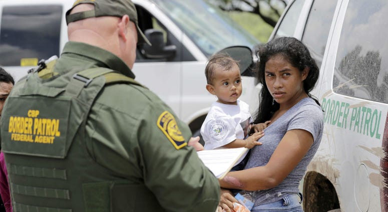 In this June 25, 2018, file photo, a mother migrating from Honduras holds her 1-year-old child as surrendering to U.S. Border Patrol agents after illegally crossing the border near McAllen, Texas. In this June 25, 2018, file photo, a mother migrating from Honduras holds her 1-year-old child as surrendering to U.S. Border Patrol agents after illegally crossing the border near McAllen, Texas.