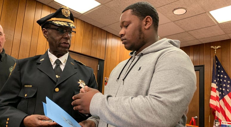 Camden County Sheriff Gilbert Wilson presents 18-year-old Kenney Smith with honorary coins for his selfless act of bravery, Dec. 12, 2019. He cared for a young girl after gunfire broke out during a high school football game on Nov. 15. Sheriff Gilbert Wilson presents Kenney Smith with honorary coins for bravery.