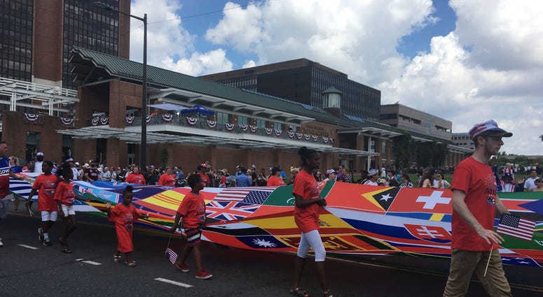 A banner representing the flags of the world marches by in the 2019 Independence Day Parade. A banner representing the flags of the world marches by in the 2019 Independence Day Parade.