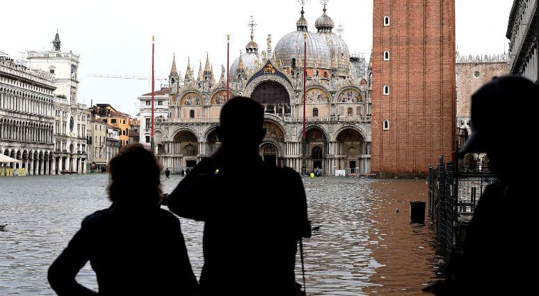 Tourists take pictures in the flooded St. Mark Square during a high-water alert in Venice on Monday.