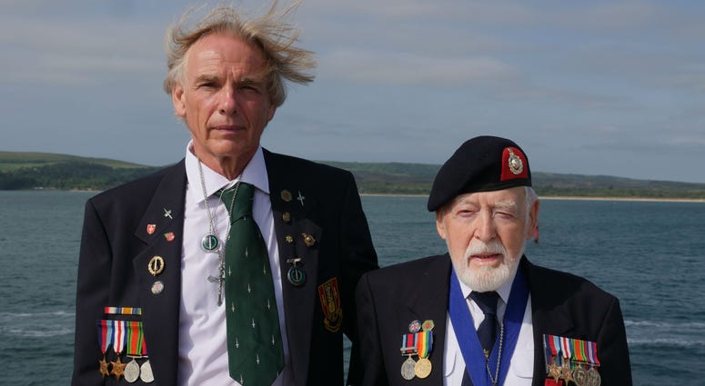 Former Royal Marine Les Budding, right, stands with Philip Collins, 62, who is the son of the late F.E. Collins of 45 Commando, who fought alongside Budding on D-Day, as they pose for a photo aboard the MV Boudicca ship. Former Royal Marine Les Budding, right, stands with Philip Collins, 62, who is the son of the late F.E. Collins of 45 Commando, who fought alongside Budding on D-Day, as they pose for a photo aboard the MV Boudicca ship.