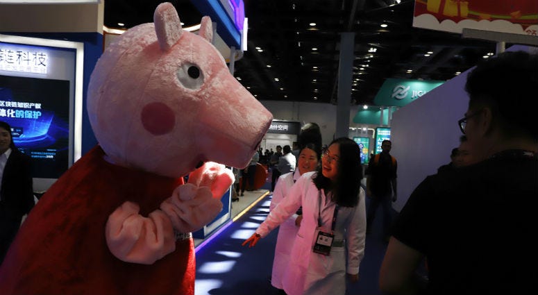 In this April 27, 2018 photo, a woman reacts to a Peppa Pig mascot during the Global Mobile Internet Conference (GMIC) in Beijing, China. a woman reacts to a Peppa Pig mascot