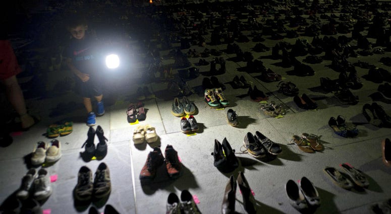 In this June 1, 2018 file photo, a child shines a light on hundreds of shoes at a memorial for those killed by Hurricane Maria, in front of the Puerto Rico Capitol in San Juan. In this June 1, 2018 file photo, a child shines a light on hundreds of shoes at a memorial for those killed by Hurricane Maria, in front of the Puerto Rico Capitol in San Juan.