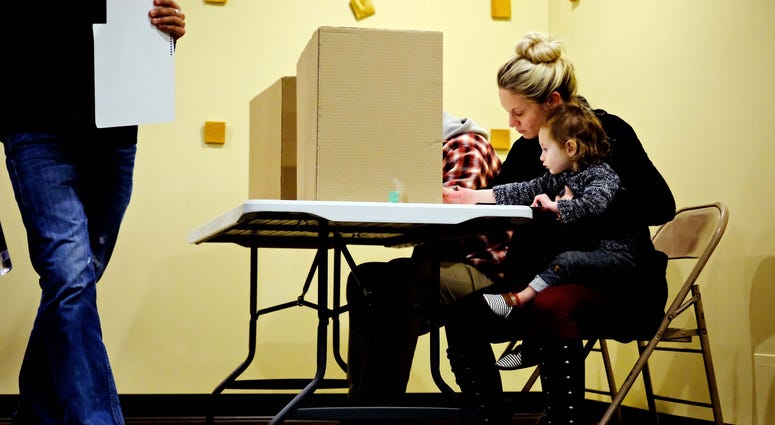 Nov 8, 2016; Frendale, MI, USA; Jenna Townsend, 32, holds her daughter Isla Townsend, 1, as she fills her ballot during the 2016 United States presidential elections at Renaissance Vineyard Church. Nov 8, 2016; Frendale, MI, USA; Jenna Townsend, 32, holds her daughter Isla Townsend, 1, as she fills her ballot during the 2016 United States presidential elections at Renaissance Vineyard Church.