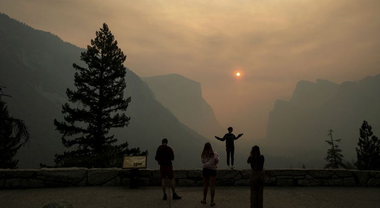 In this July 25, 2018 file photo, Hannah Whyatt poses for a friend's photo as smoke from the Ferguson fire fills Yosemite Valley in Yosemite National Park, Calif. In this July 25, 2018 file photo, Hannah Whyatt poses for a friend's photo as smoke from the Ferguson fire fills Yosemite Valley in Yosemite National Park, Calif.