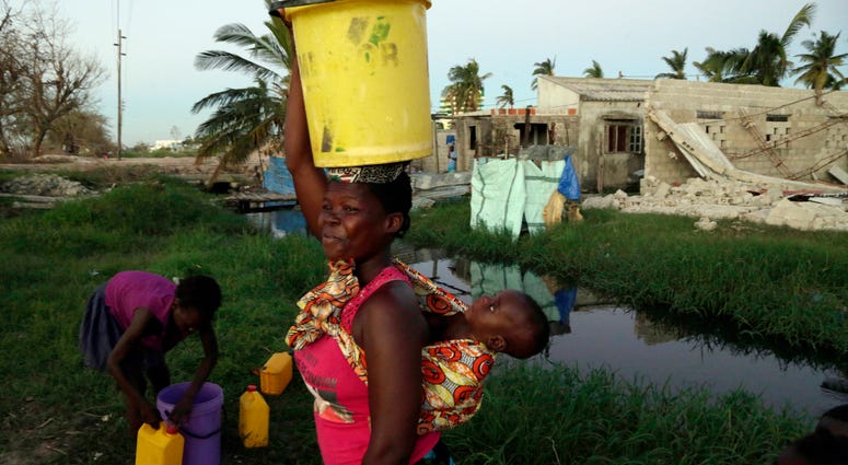 A woman carrying water and a baby on her back after collecting water in Beira, Mozambique, Monday, March 25, March 24, 2019. A woman carrying water and a baby on her back after collecting water in Beira, Mozambique, Monday, March 25, March 24, 2019.