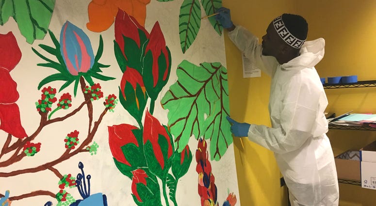 Belo, 25, paints a section of a mural as part of a Mural Arts same-day pay program. Belo, 25, paints a section of a mural as part of a Mural Arts same-day pay program.