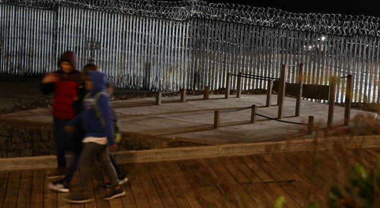 Floodlights from the U.S, illuminate the border wall, topped with razor wire, as a people pass Monday, Jan. 7, 2019, at the beach in Tijuana, Mexico. Floodlights from the U.S, illuminate the border wall, topped with razor wire, as a people pass Monday, Jan. 7, 2019, at the beach in Tijuana, Mexico.