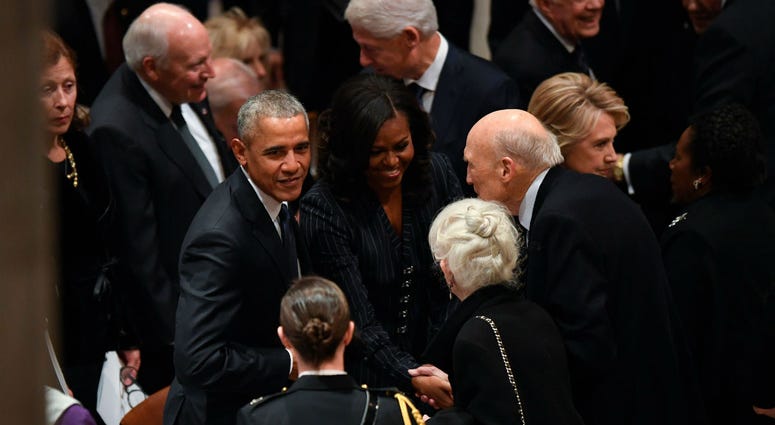Former President Barack Obama and his wife, Michelle Obama, greet former Sen. Alan Simpson as former President George H.W. Bush before a state funeral at the Washington National Cathedral in Washington, Dec. 5, 2018. Former President Barack Obama and his wife, Michelle Obama, greet former Sen. Alan Simpson as former President George H.W. Bush before a state funeral at the Washington National Cathedral in Washington, Dec. 5, 2018.