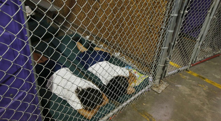 In this June 18, 2014 file photo, two female detainees sleep in a holding cell, as hundreds of mostly Central American immigrant children are being processed and held at the U.S. Customs and Border Protection Nogales Placement Center in Nogales, Ariz. two female detainees sleep in a holding cell
