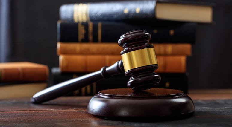 Law gavel on a wooden desk, law books background Gavel