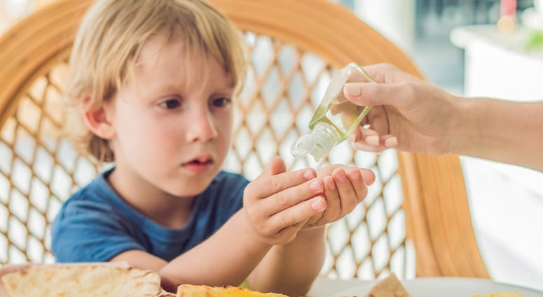 Boy using wash hand sanitizer gel in the cafe. hand santizer