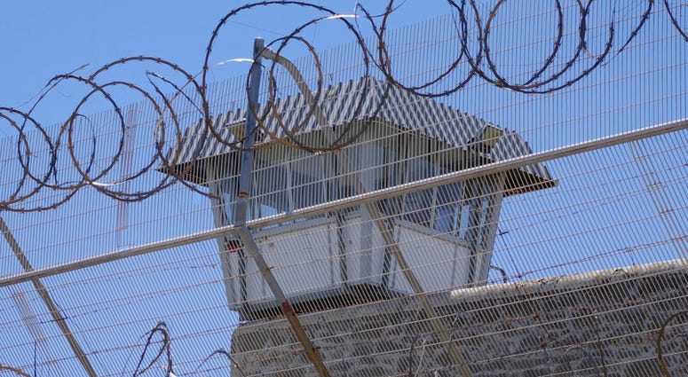 File photo of prison barbed fence and guard tower behind Prison