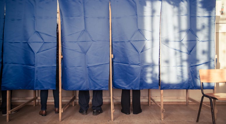 People vote in a voting booth at a polling station. Voting Booth