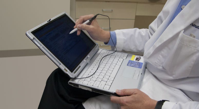 Doctor entering patient information into a laptop designed specifically for medical personnel. electronic medical records